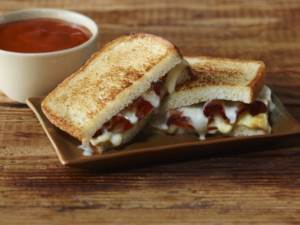 Grilled cheese sandwich on plate next to soup